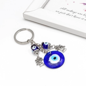 Detail of blue glass Evil Eye keychain with silver palm and coconut tree pendants