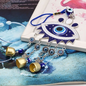Detail of blue Nazar evil eye wall hanging with metal Hamsa palm and brass bells