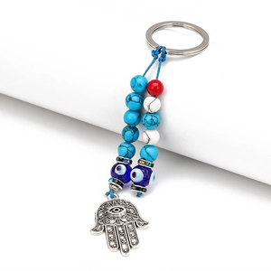 Macro shot of silver Hamsa Hand keychain with blue evil eye beads and colorful stone details
