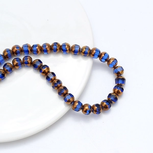 Macro de perles facettées bleues et bronze sur un bracelet élastique sur fond blanc épuré
