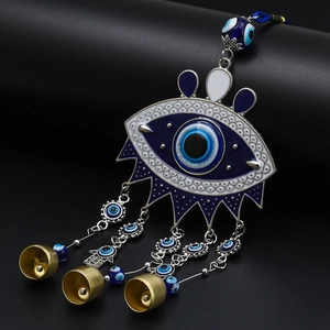 Detail of blue evil eye wall hanging with golden metal bells and Hamsa hand charm