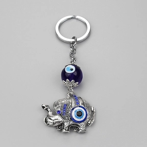 Silver elephant keychain with blue evil eye beads and rhinestones on a grey background