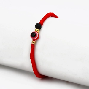 Macro shot of red braided Evil Eye bracelet with lava stone and gold beads decoration