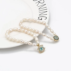 Bracelet en perles baroques avec pendentifs œil bleu sur une assiette en céramique