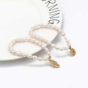 Bracelet en perles d'eau douce avec breloques main de Fatma dorée et œil bleu zircon