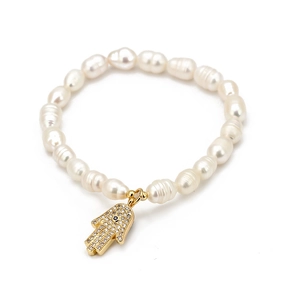 Bracelet de perles baroques avec breloque Main de Fatma dorée et œil bleu sur fond blanc