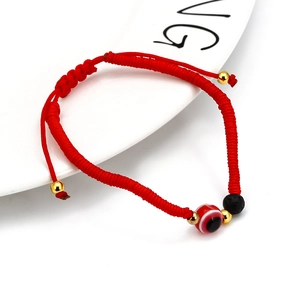 Detailed close-up of red braided rope evil eye bracelet with black lava stone bead and gold beads
