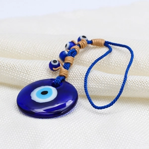 Macro shot of blue glass Evil Eye charm with woven rope and small bead details