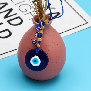 Blue Turkish evil eye lucky charm with glass beads hanging on a decorative ceramic vase