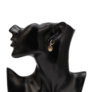 Detail view of gold hoop earring with blue gemstone evil eye pendant on model