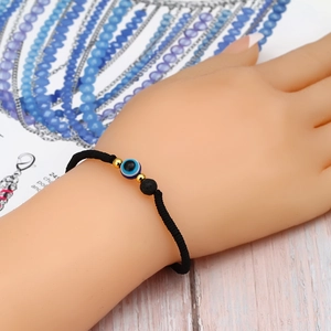 Adjustable red rope bracelet with blue Evil Eye bead, gold beads and black volcanic stone