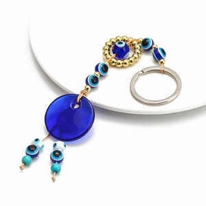 Close-up of Turkish Evil Eye charm with blue glass pendant and gold beads keychain