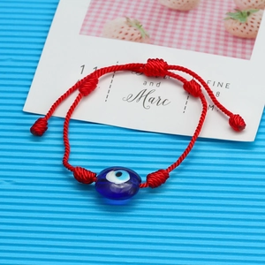 Gros plan sur le bracelet tressé rouge avec perle œil bleu maléfique et nœud ajustable