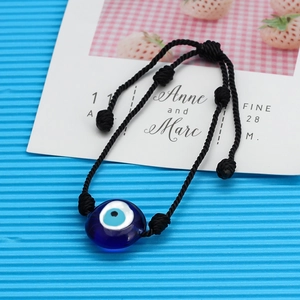 Détail d'une perle en verre œil bleu sur un bracelet noir réglable tissé à la main