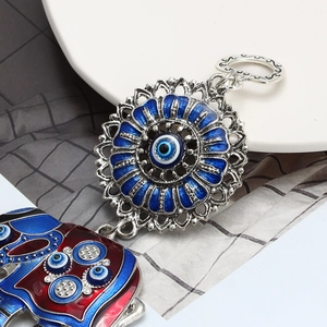 Detailed view of enamel elephant charm and blue evil eye pendant with silver keychain