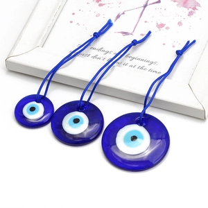 Three sizes of blue glass evil eye hanging ornaments with matching woven strings on white base