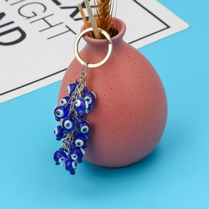 Detailed view of evil eye lucky charm keychain with blue resin beads hanging on pink vase