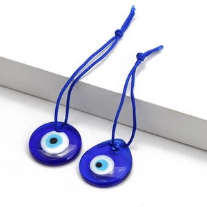 Deep blue glass evil eye pendant set with round and teardrop shapes on white podium
