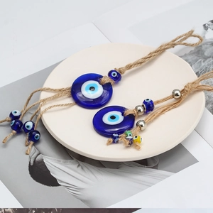 Blue glass evil eye pendants with hemp rope on a minimalist ceramic plate decor