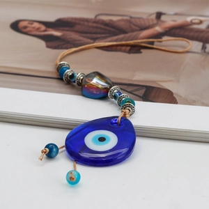 Macro shot of glass Evil Eye water drop pendant with metallic heart and blue beads