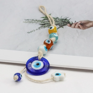 Detail of Turkish evil eye glass charm with multi-color beads and handmade hemp rope hanging