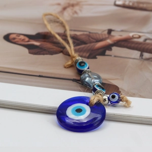 Macro detail of Turkish Evil Eye glass pendant with rustic hemp rope and metallic beads