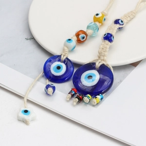 Detail of blue glass Evil Eye pendant with white cotton hand-woven rope and colorful beads
