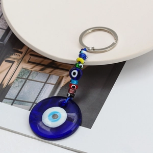 Dettaglio del portachiavi turco Evil Eye in vetro blu con perline su vassoio bianco