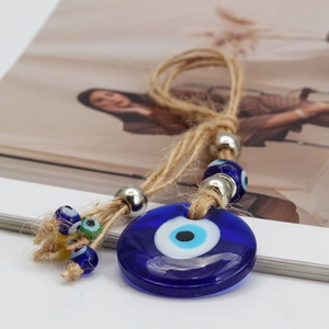 Macro shot of glass evil eye pendant with braided rope on warm decorative background