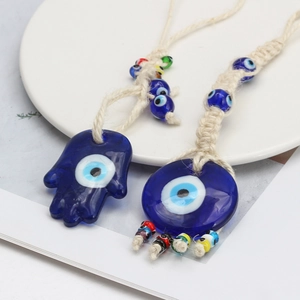 Detailed macro view of glass evil eye charms with Hamsa hand and cotton rope hangers