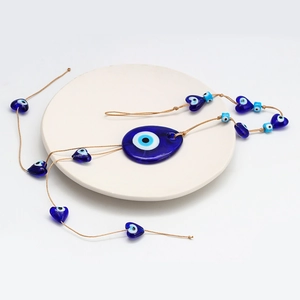 Detailed view of Turkish Evil Eye glass charm with heart-shaped blue beads on tray