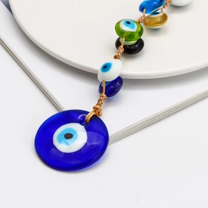 Macro detail of Evil Eye glass pendant with multi-colored beads on a white ceramic plate