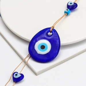 Detail of tear-shaped blue glass Evil Eye pendant with heart-shaped protective bead