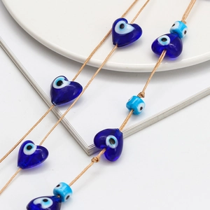Detailed macro view of heart-shaped blue evil eye glass beads on a braided string cord