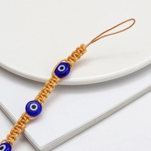 Detailed macro shot of hand-woven evil eye charm strap with blue beads and beige cord