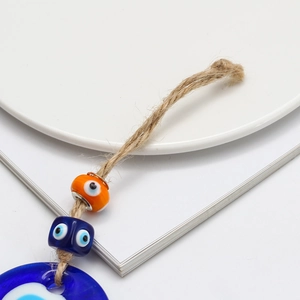 Detail of Turkish blue glass Evil Eye pendant with orange beads and jute rope