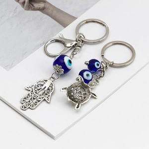 Dettaglio dei ciondoli mano di Fatima e tartaruga con perline occhio blu sui portachiavi