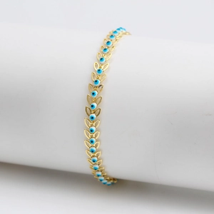 Pulsera de ojo turco dorado con eslabones de hoja de trigo en soporte cilíndrico blanco