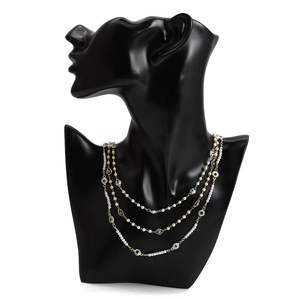 Détail d'un collier doré multicouche avec perles blanches et pendentifs œil maléfique
