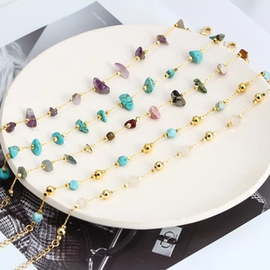 Bohemian gold chain bracelets with colorful natural crushed stones in a white porcelain dish