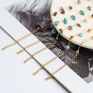 Golden link chain bracelet with natural gravel stones and evil eye beads on magazine