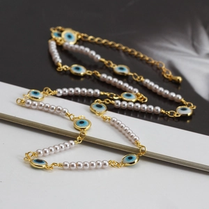 Détail du collier œil porte-bonheur doré avec perles blanches et breloques bleues chic