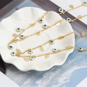 Dettaglio di collana bohémien in oro con mano di Hamsa e ciondoli occhio blu su porcellana