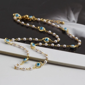 Détail du collier mauvais œil avec perles blanches et chaîne plaquée or fin