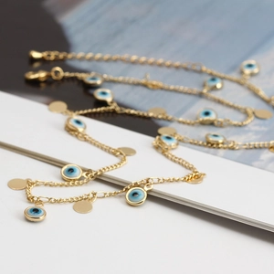 Dettaglio di cavigliere dorate Evil Eye con ciondoli in smalto blu e catenella regolabile