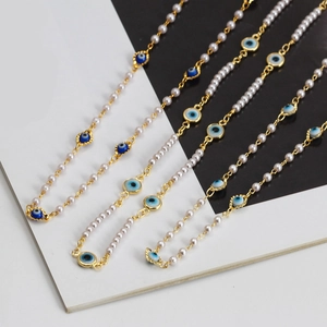 Détail du bracelet en perles avec charmes œil en émail bleu et fermoir doré chic