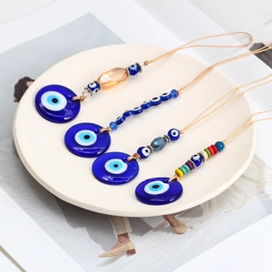 Detail of four handmade glass evil eye charms with assorted beads in a white tray