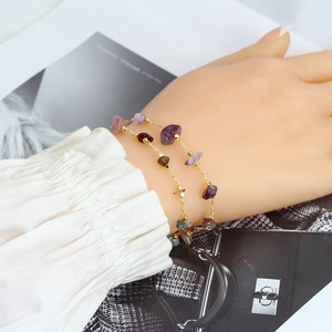 Close-up of double-layer gold chain bracelet with colorful natural gemstone chips on wrist