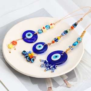 Detail view of woven Evil Eye glass pendants with heart beads on a ceramic plate