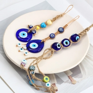 Three assorted evil eye charms with blue glass beads and jute rope on a ceramic plate